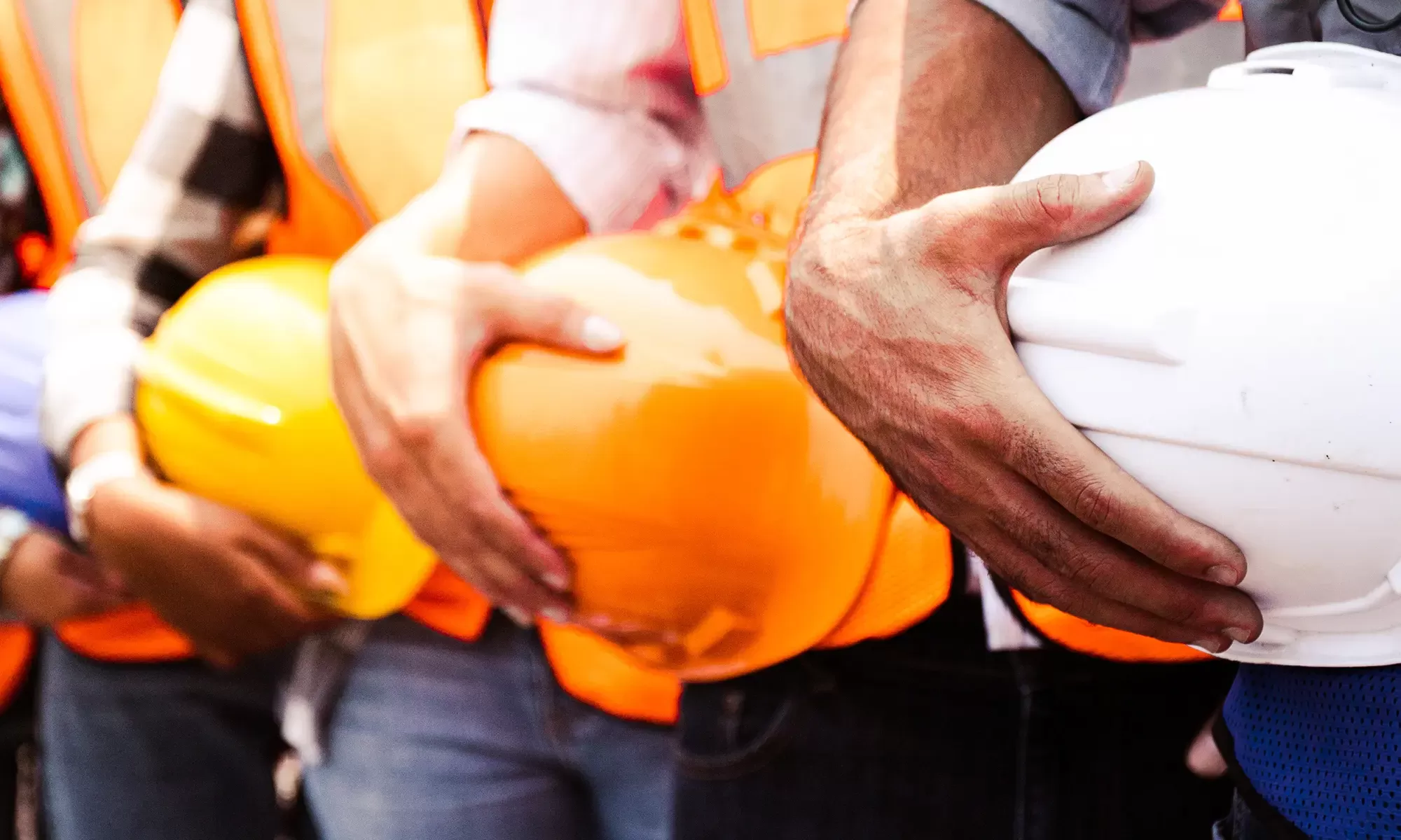 Workers holding helmets as a team